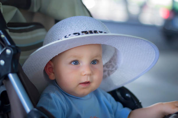 Baby with nice blue cap crawling on the green grass in the garden and smiles