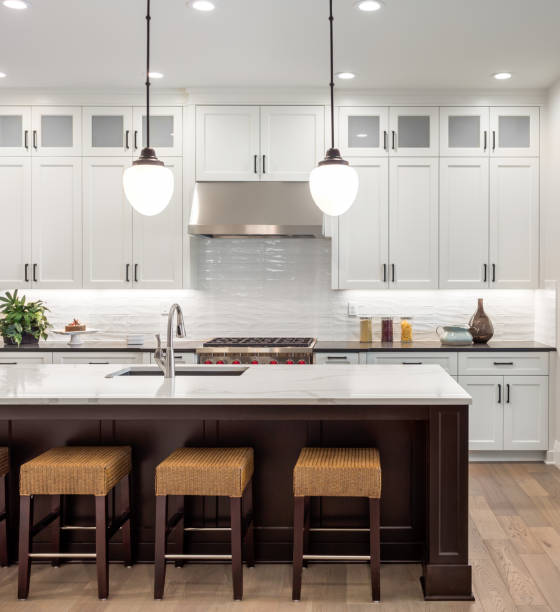 beautiful kitchen in new luxury home with island, pendant lights, oven, range, and hardwood floors. stock photo