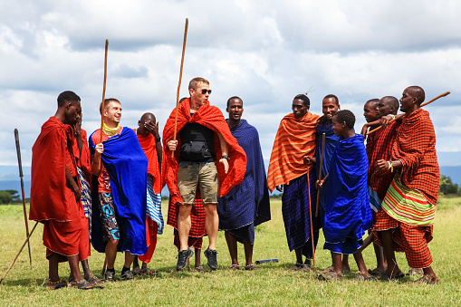 Africa, Tanzania, Masai village - March 04, 2016:      European tourists and locals perform the national dance of the Masai tribe