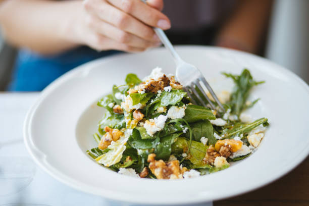 młoda kobieta jedząca sałatkę wegeteryjską w restauracji na lunch - vegeterian food zdjęcia i obrazy z banku zdjęć