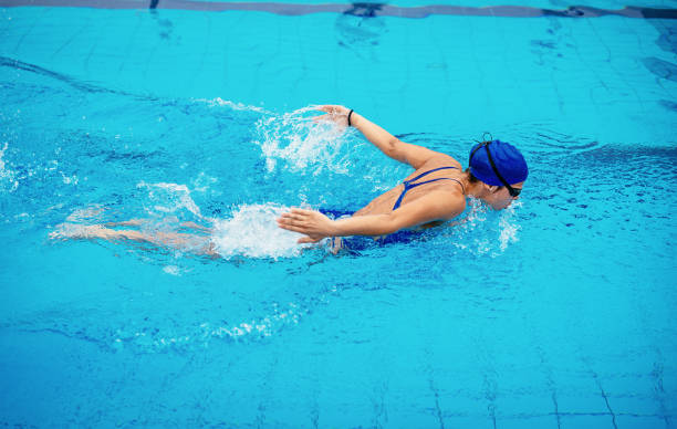 Woman in pool, swimming butterfly stroke Female swimmer on evening training on swimming pool, warming up, swimming freestyle and butterfly during training. She is determined to win women exercising swimming pool young women stock pictures, royalty-free photos & images