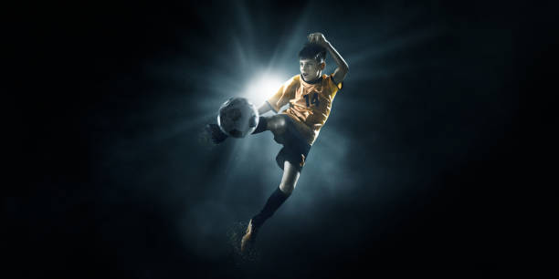 istock Soccer kids player kicking ball in spotlight 697427150
