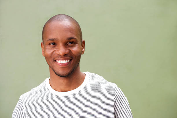 istock Close up smiling young black man against green background 697427218