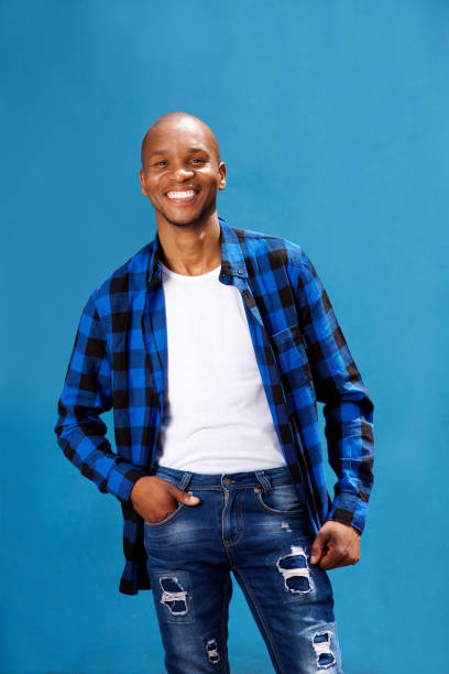 istock smiling young man standing against blue background 697427242