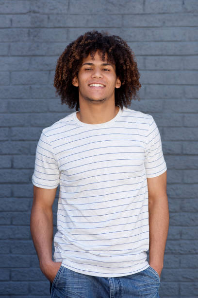 istock cool young man smiling against gray wall 697427334