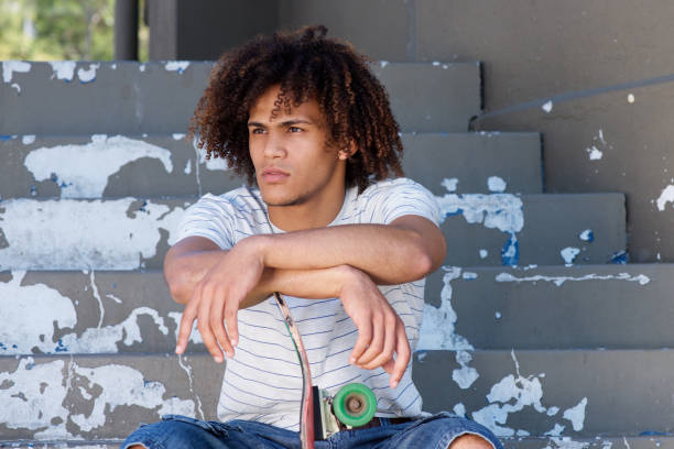 istock handsome young man sitting on steps with skateboard 697427386