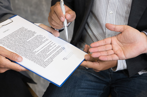 Businessman and lawyer negotiating a contract, they are pointing on a document and discussing together in a meeting. business colleagues working at office workplace