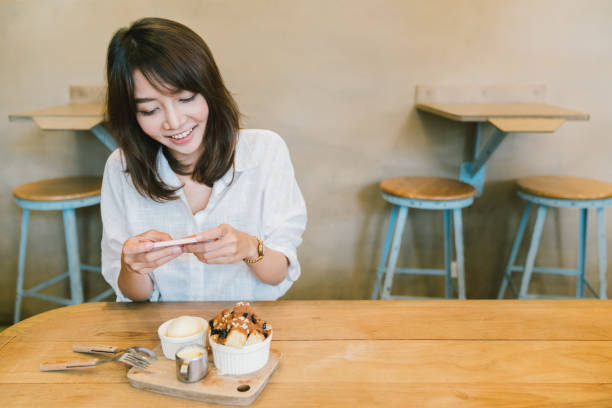 beautiful asian girl taking photo of chocolate toast cake, ice-cream, and milk at coffee shop. dessert or food photograph hobby. smartphone or mobile phone photography habit concept. with copy space - japanese maple imagens e fotografias de stock