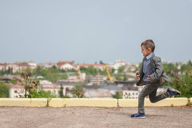 istock funny little boy runs along border along the cityscape 697435542