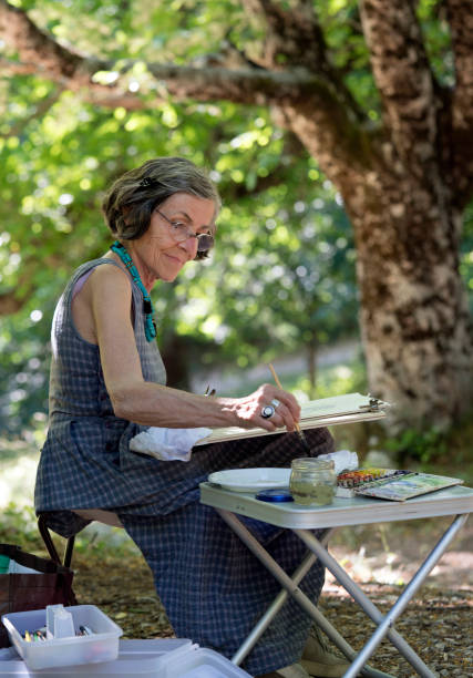 istock Senior woman painting outdoors, vertical 697438510