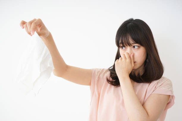 Young woman smelling stinky laundries Young woman smelling stinky laundries laundry husband housework men stock pictures, royalty-free photos & images