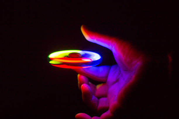 istock Play Fidget spinner spinning and Hand on dark background With Ligtht 697446114
