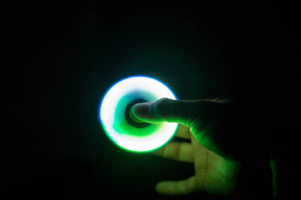 istock Play Fidget spinner spinning and Hand on dark background With Ligtht 697446166