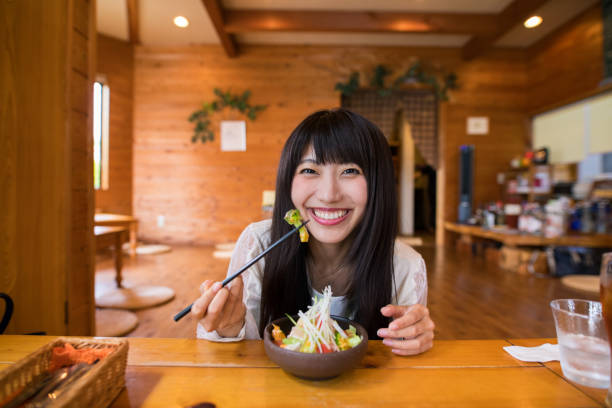 happy young woman eating salad for lunch at log cabin restaurant - salad japanese culture japan asian culture imagens e fotografias de stock