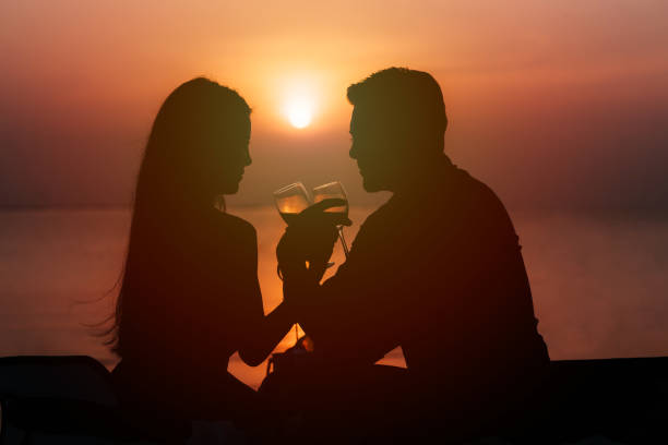 Silhouette of couple in love drinking wine during romantic dinner