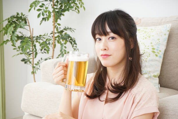 istock Young woman drinking beer at home 697459938