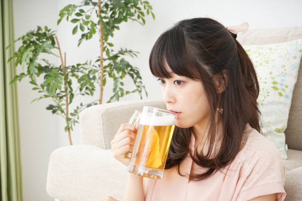 istock Young woman drinking beer at home 697459952