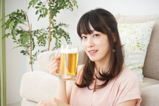 istock Young woman drinking beer at home 697459954