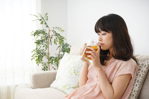 istock Young woman drinking beer at home 697459958