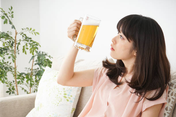 istock Young woman drinking beer at home 697459962