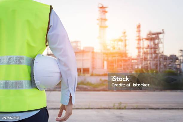 Photo libre de droit de Homme De Génie Debout Avec Un Casque De Sécurité Blanc Près De Raffinerie De Pétrole banque d'images et plus d'images libres de droit de Chantier de construction