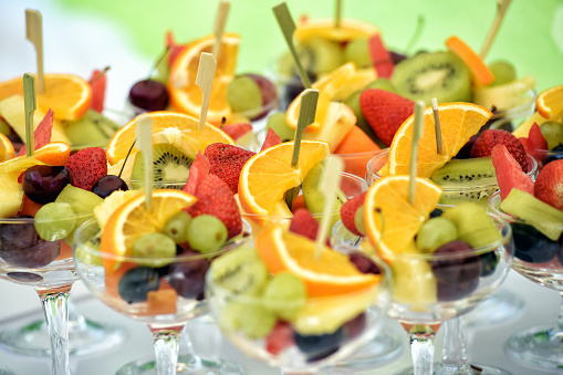 Colorful assortment of fresh fruit cocktails in glasses displayed on a buffet table at a catered event for a healthy appetizer or dessert