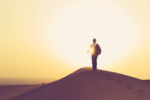 teenager walking towards the rising sun on the arabian dunes - liwa desert imagens e fotografias de stock