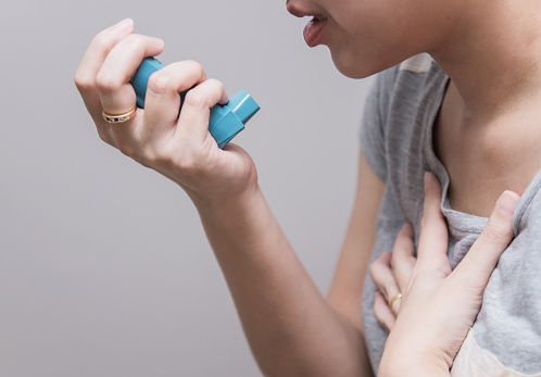 Mujer asiática con un inhalador de cartucho presurizado extiende faringe, broncodilatador photo