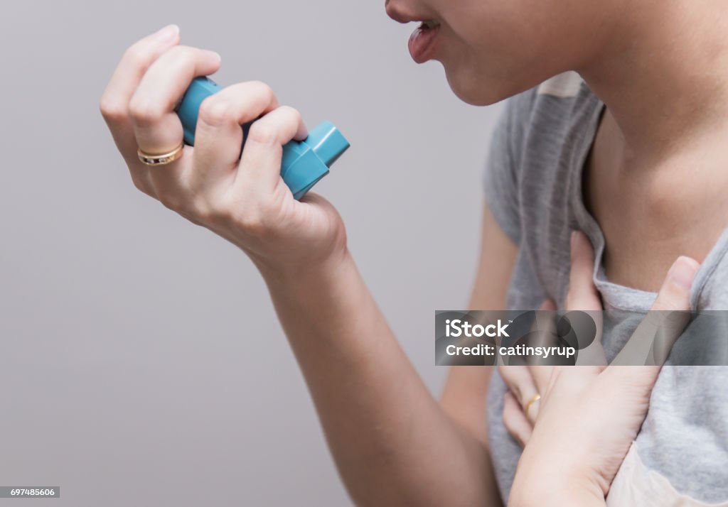 Asian woman using a pressurized cartridge inhaler extended pharynx, Bronchodilator Asthmatic Stock Photo