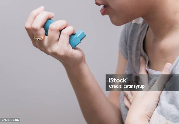 Asian Woman Using A Pressurized Cartridge Inhaler Extended Pharynx Bronchodilator Stock Photo - Download Image Now