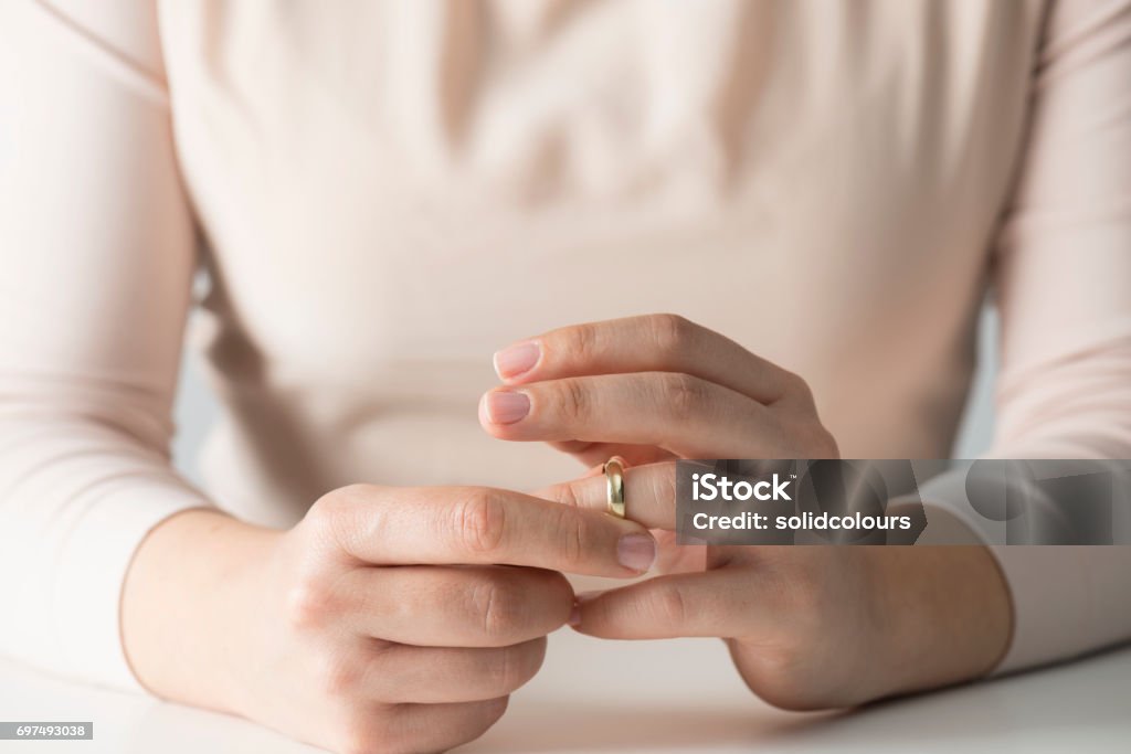 Woman Getting Divorced Woman taking off wedding ring. Divorce Stock Photo