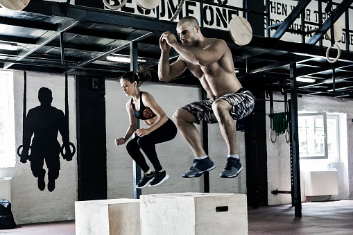 Man and woman working out in gym jumping