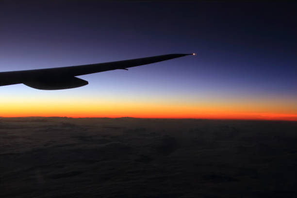 istock Airplane wing, warn and cold colors through from window silhouette 697524660