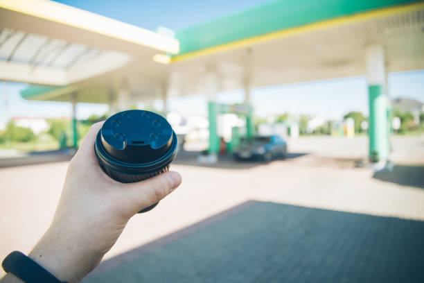 man with coffee cup going to his car on gas station