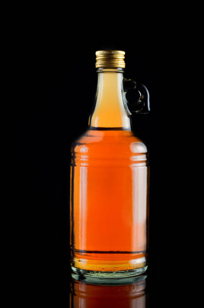 istock Apple Cider Vinegar in a glass bottle over black background 697531860