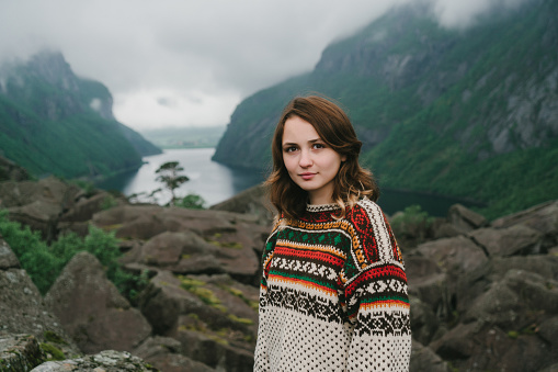 Young Caucasian woman in knitted sweater standing near the lake in Norway