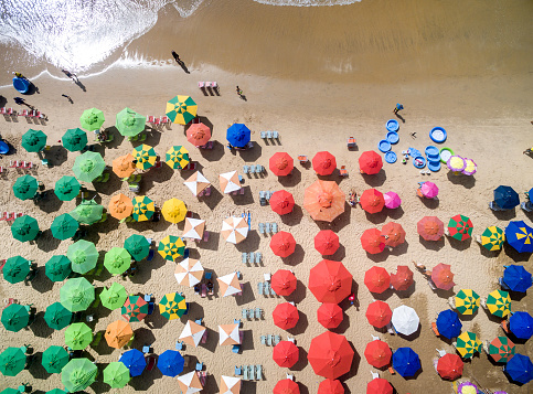 Beach umbrella near towel and other vacationist's stuff on sand, aerial view. Space for text