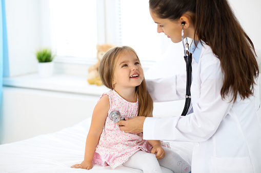 Doctor examining a little girl by stethoscope.