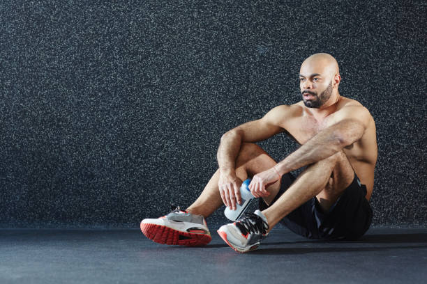 istock Muscular Man Sitting on Floor against Wall 697565736