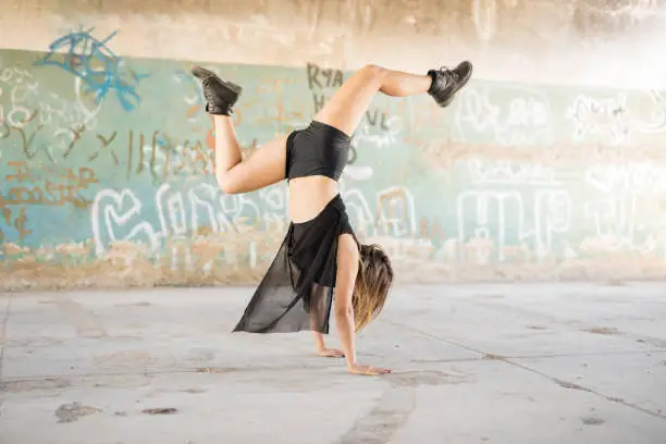 Full length view of a female contempo dancer doing a handstand while performing in an abandoned building