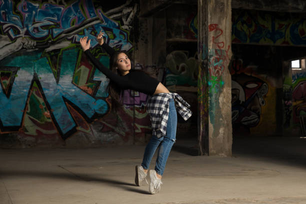 Beautiful urban dancer standing on her toes while dancing in front of a graffiti wall
