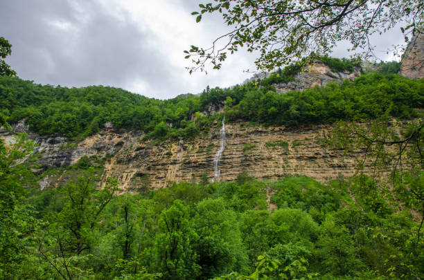 chute d’eau sur une montagne de rocher. fond d’écran paysage nuageux avec le vert de la forêt du caucase. gorge de guam - waterfall rock mountain bright photos et images de collection