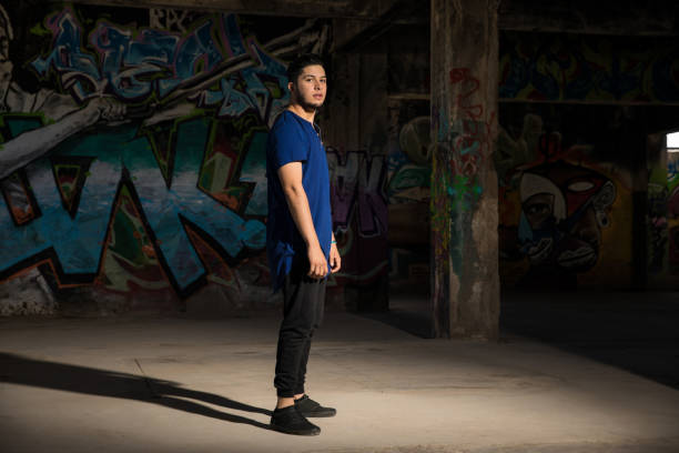 Full length portrait of a good looking Hispanic male dancer getting ready to dance against a graffiti wall