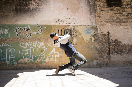 Portrait of a good looking Hispanic male dancer freestyling outdoors in an abandoned building