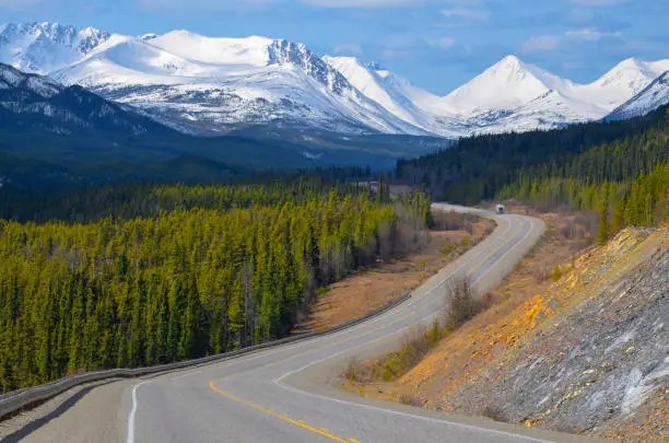 Scenic view of the Alaska Highway in the Yukon, Canada, with snow covered mountains and conifer woods