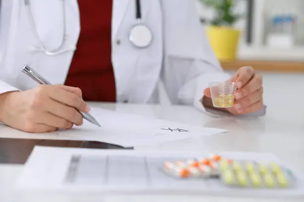 Photo of Female medicine doctor fills up  prescription form to patient closeup. Panacea and life save, prescribe treatment, legal drug store, contraception concept