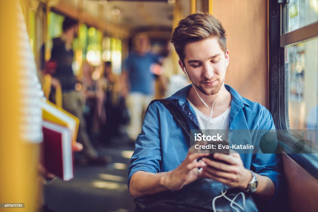 Checking messages Young man checking messages on his smart phone Bus Stock Photo