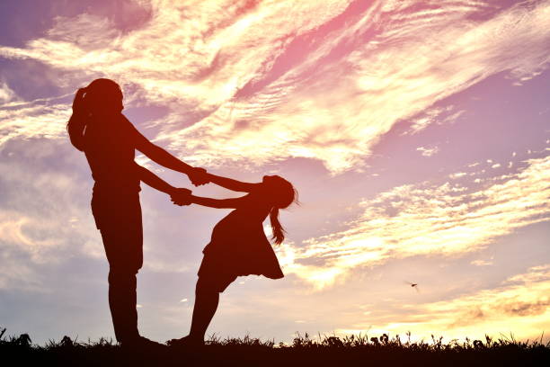 istock Mother And Daughter Playing Against Cloudy Sky During Sunset 697613153