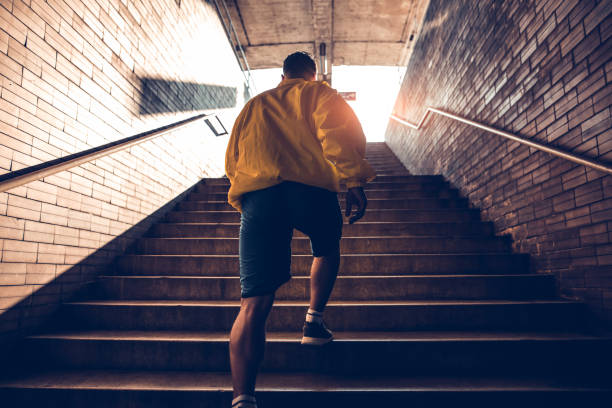 istock Sporty man running up steps in urban setting 697622224