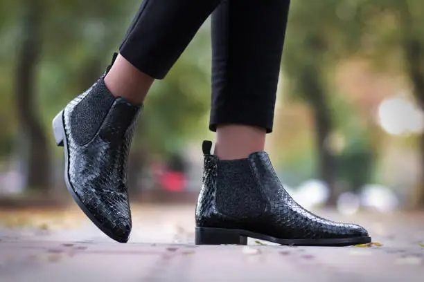 A girl steps in python leather shoes. The girl is walking in the shoes along the street